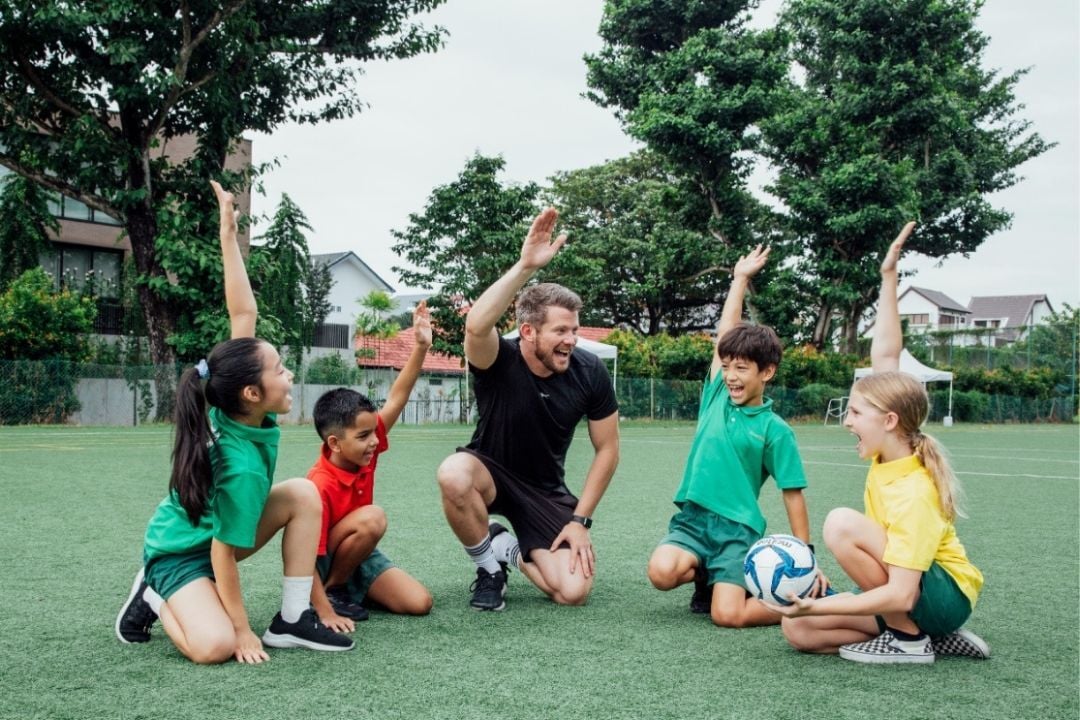 EtonHouse Broadrick students participating in a PE lesson on the sports field with their teacher.